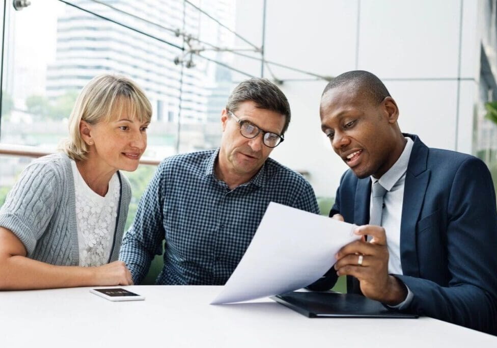 A man and two women looking at papers.